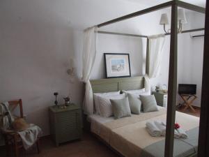 a bedroom with a canopy bed with white pillows at Stavento Apartments in Aliki