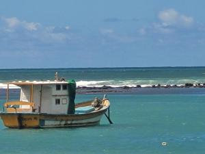 a boat sitting in the water near a beach at Pousada Mirante de Porto in Porto De Galinhas