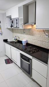 a kitchen with white cabinets and a stove top oven at FLAT Maré Alta - Porto de Galinhas in Porto De Galinhas +26 photos