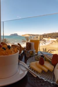a table with a plate of food with a view of the beach at La Sort Boutique Hotel in Moraira