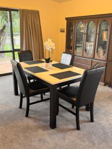 a dining room table and chairs with a table and a cabinet at Woodbank Retreat in Hanmer Springs