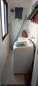 a small kitchen with a sink and a washing machine at Apartamento em Enseada Guarujá in Guarujá