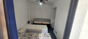 a small room with two beds and a ceiling fan at Apartamento em Enseada Guarujá in Guarujá