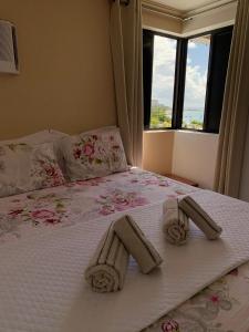 a bed with two towels on it with a window at Residencial Neo 1 in Maceió