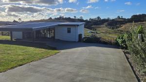 a small white house with a driveway in front of it at Bever Farm in Waitoki