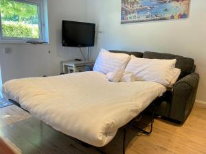 Cama en habitación con sofá y TV en Little Wight House - Yarmouth, en Freshwater