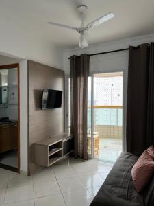a living room with a bed and a television at Apto com Ar condicionado e churrasqueira in Praia Grande