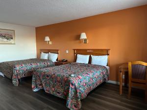 2 Betten in einem Hotelzimmer mit orangefarbenen Wänden in der Unterkunft Regal Inn Las Vegas New Mexico in Las Vegas