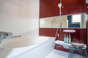 eine weiße Badewanne im Bad mit roten Wänden in der Unterkunft Torenia in Furano