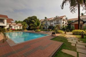 a swimming pool in a yard with houses at Dream key suits in Siolim