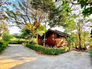a wooden house with a driveway in front of it at Panpim Resort in Ban Noen Hom