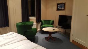 ハウゲスンにあるSkeisvang Gjestgiveriの緑の椅子2脚とテレビが備わるホテルルームです。