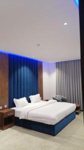 a bedroom with a large bed with a blue wall at شقق زهرة النزلاء المخدومة الخرج in Al Kharj +69 photos