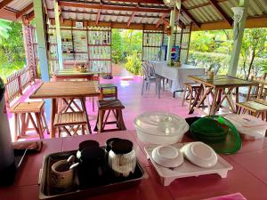 a table with plates and bowls and tables and chairs at Panpim Resort in Ban Noen Hom