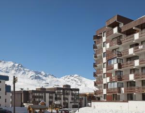 un grand immeuble d'appartements devant une montagne enneigée dans l'établissement Abrineige Le Schuss Val Thorens, à Val Thorens