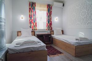 een kamer met twee eenpersoonsbedden en een raam bij XIVA AZIM OTA in Khiva