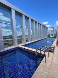 a swimming pool on the side of a building at M&V Flats - Prédio Vision - 1,5 km Mané Garrincha - 500m Esplanada dos Ministérios - Vaga de garagem - Ar condicionado - Cama queen size - Piscina - Academia in Brasilia