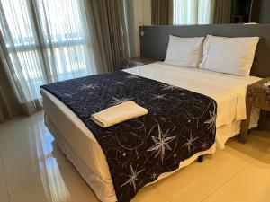 a bedroom with a bed with a black and white blanket at M&V Flats - Prédio Vision - 1,5 km Mané Garrincha - 500m Esplanada dos Ministérios - Vaga de garagem - Ar condicionado - Cama queen size - Piscina - Academia in Brasilia +5 photos