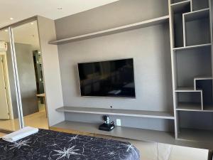 a bedroom with a flat screen tv on a wall at M&V Flats - Prédio Vision - 1,5 km Mané Garrincha - 500m Esplanada dos Ministérios - Vaga de garagem - Ar condicionado - Cama queen size - Piscina - Academia in Brasília