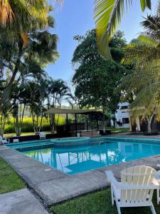 a swimming pool with two white chairs and trees at Casa Nael a 2Km del IRTRA in San Martín Zapotitlán