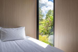 - un lit avec un oreiller en face d'une fenêtre dans l'établissement Chain of Ponds Cottage by Tiny Away, à Tamaree 4 autres photos