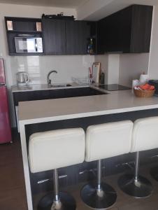 a kitchen with white counter tops and white bar stools at Departamento Familiar con vista al Mar in Viña del Mar +6 photos