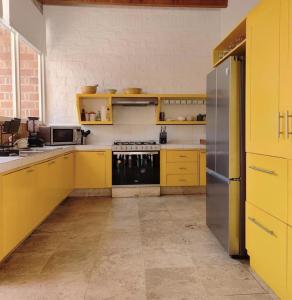 a kitchen with yellow cabinets and a stainless steel refrigerator at Casa María de mi Corazón in Tepoztlán