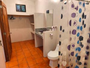 a bathroom with a toilet and a shower curtain at Casa 3 amigas in Troncones