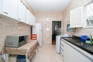 a small kitchen with a microwave and a sink at Quarto amplo ao lado do mar in João Pessoa
