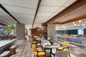 un rendering di un ristorante con tavoli e sedie di Hilton Garden Inn Tianjin Five Great Avenues a Tianjin