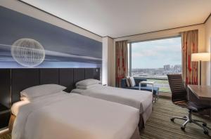 大園区にあるHyatt Regency Taoyuan International Airportのベッド2台、デスク、窓が備わるホテルルームです。 +32枚の写真