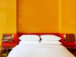 a bed with white pillows against a yellow wall at The Manner, The Unbound Collection by Hyatt in New York