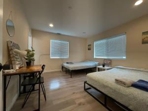 a bedroom with two beds and a table and a desk at The Disney Hostel - Santa Ana in Santa Ana