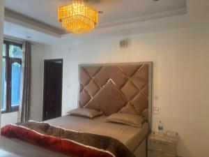 a bedroom with a bed with a headboard and a chandelier at Anayah B and B in Shimla