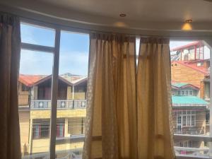 a window with curtains and a view of a building at Anayah B and B in Shimla