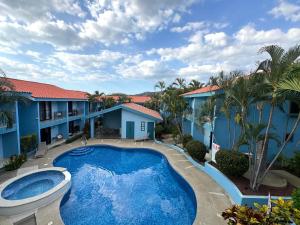 a pool in front of a house with palm trees at Pineapple Condo at Villa Riviera in Coco