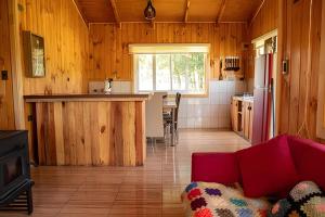 a living room with a red couch and a kitchen at Parque Vera Cabaña 1 in Melipeuco