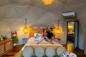a man and woman sitting on a bed in a tent at Beachfront Luxury Dome Villas - Gamat Bay Resort in Nusa Penida