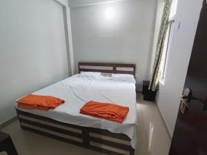 a bedroom with a bed with white sheets and orange sheets at RAGHAV SADAN Luxury Apartment in Prayagraj