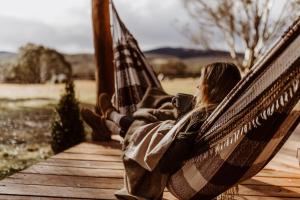 a woman sitting in a hammock with a cup of coffee at Kallarroo Farmstay in Snowy Mountains in Nimmitabel