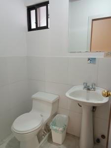 a white bathroom with a toilet and a sink at Hostal Your Home in Quito