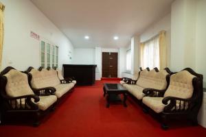 Casspo Forest Bungalow في Kallar Vattiyar: غرفة معيشة بها كنب وطاولة وتلفزيون