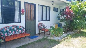 two benches sitting outside of a house at Kristel Rooms in Quepos