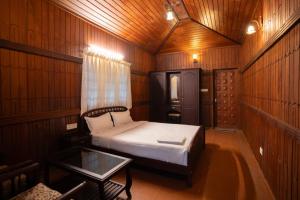 Casspo Forest Bungalow في Kallar Vattiyar: غرفة صغيرة بها سرير وطاولة