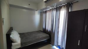 a small bedroom with a bed and a window at Suite Escapade in Manila