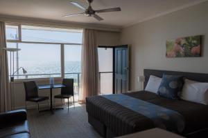 潘尼萧Seafront Hotel Kangaroo Island的酒店客房设有一张床铺和一张桌子,享有美景。