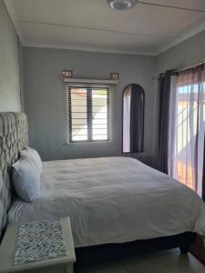 a bedroom with a large bed and a window at Palm Bliss Self Catering Accommodation in Durban +5 photos