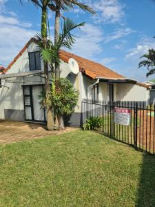 a house with a fence and a palm tree at Palm Bliss Self Catering Accommodation in Durban