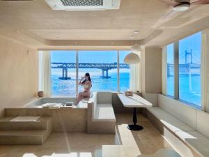 a woman in a bath tub with a view of a bridge at Meomulda Gwangalli Gamsung in Busan