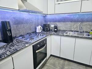 a kitchen with white cabinets and a stove and a sink at Casa Valle Viejo con Cochera Cubierta Gratis in San Fernando del Valle de Catamarca